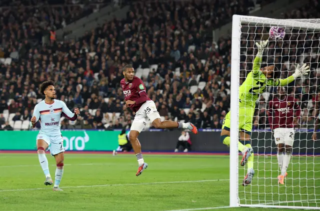 Brentford's Kevin Schade heads at goal and hits the bar