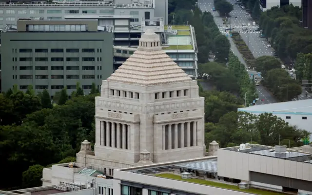 Aerial view of Japan's parliament building, a beige squarish tower with a pointed roof