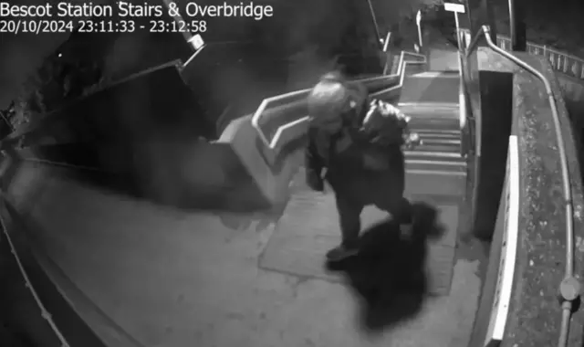 A slightly blurred black and white image of a person with light coloured hair at the top of a flight of stairs