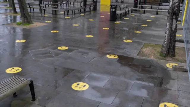 A school playground with stickers on the floor marking social distancing spaces.