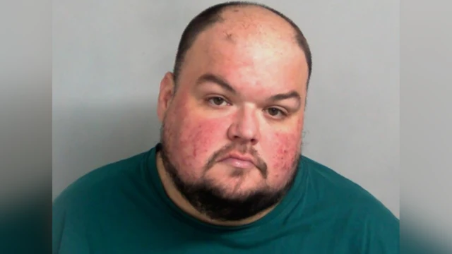 Police custody mugshot of Gavin Plumb. He has receding short hair, facial hair and a turquoise top/T-shirt