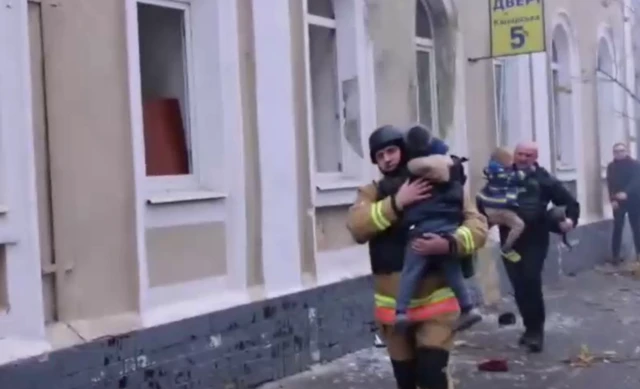 Two emergency service workers walking with children in their arms