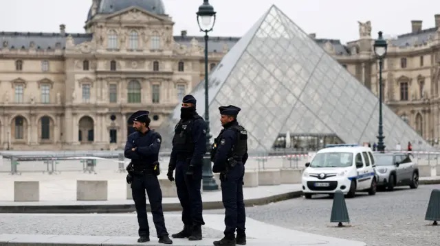 French police stand in front of a cordoned off Louvre Museum