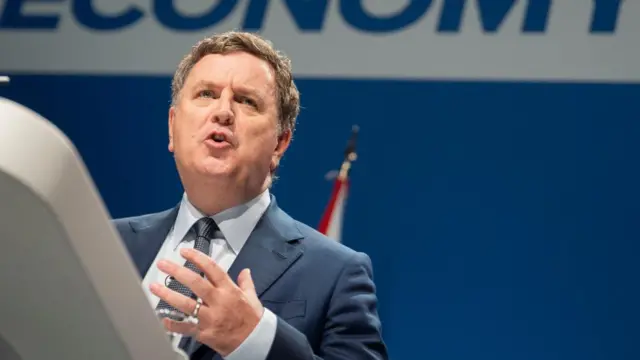 Mel Stride, shadow chancellor, speaks at an event with the words economy seen in the background