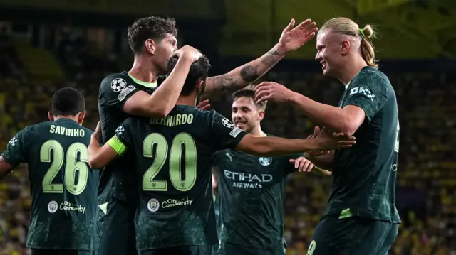 Manchester City goalscorers Erling Haaland and Bernardo Silva celebrate with John Stones