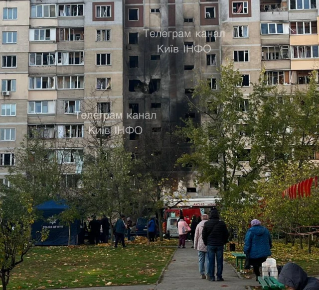 Fire damage to the front of a residential building with a crowd of people standing outside