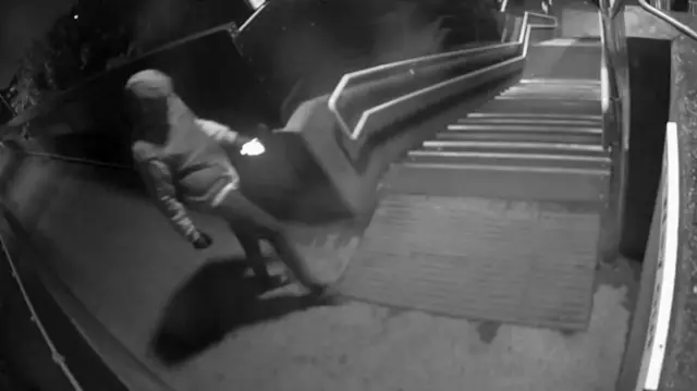 A grey figure at the top of a flight of stairs