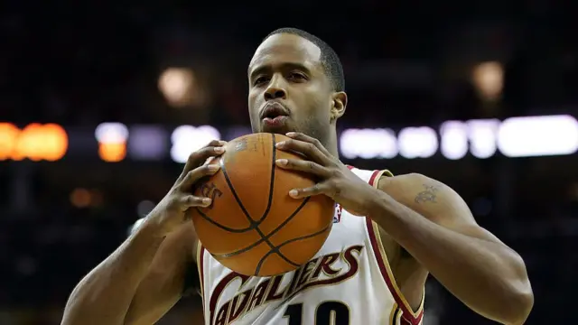 Man in a Cleveland Cavaliers basketball vest holding basketball with two hands