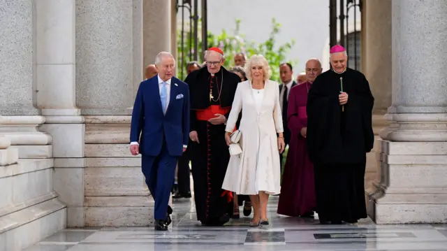 Camilla walks in wearing white