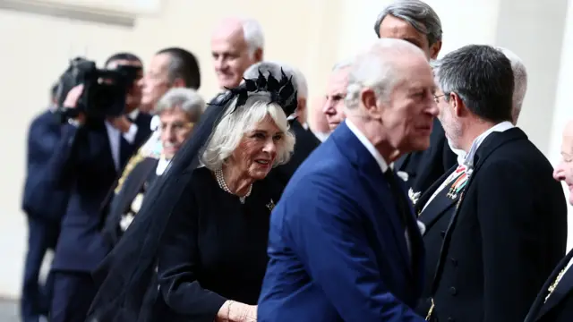 King Charles and Queen Camilla shake hands of those waiting to greet them