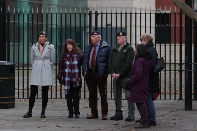 Five people in coats standing outside court