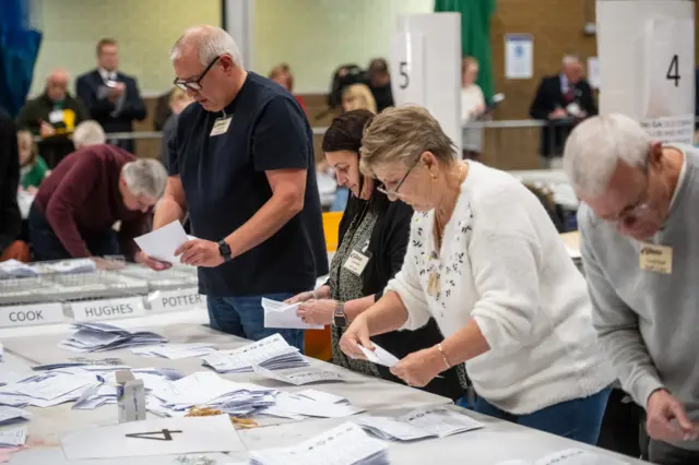 A group of people counting voting papers