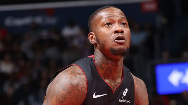 Man in black basketball vest looks upwards