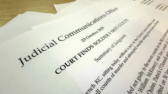 Several pages, the top one of which reads: 'Judicial Communications Office - 23 October 2025 - COURT FINDS SOLFIER F NOT GUILTY'