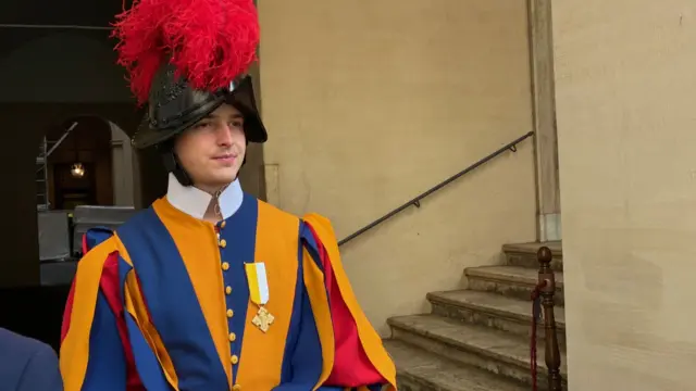 Swiss guard in helmet with red feathers and a striped shirt