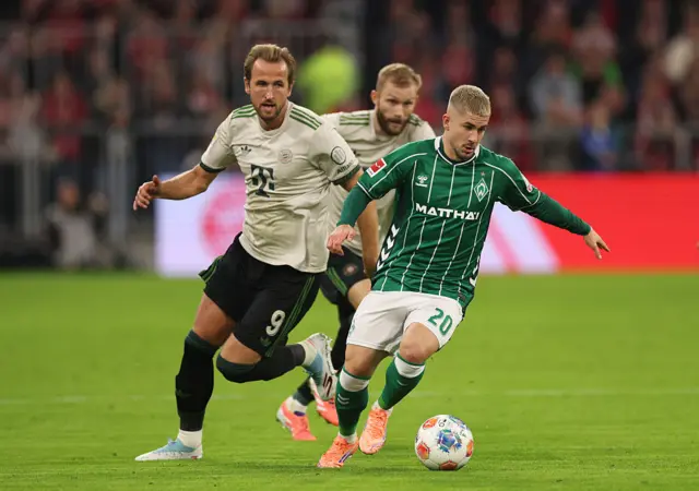 Romano Schmid of Werder Bremen runs with the ball whilst under pressure from Harry Kane