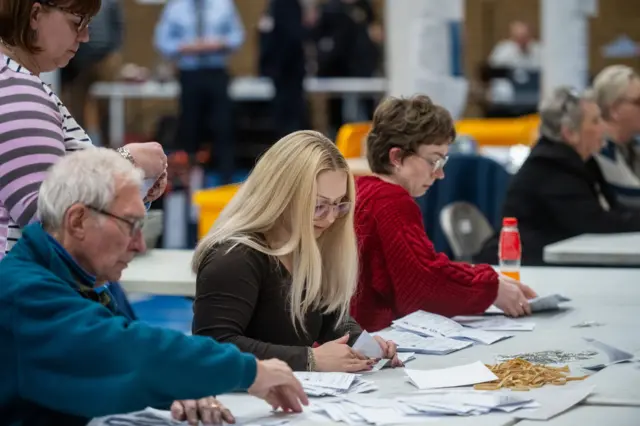 A group of people counting voting papers