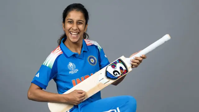 Jemimah Rodrigues holding a cricket bat like a guitar