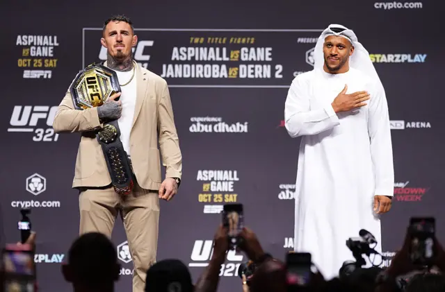 Tom Aspinall holds the UFC heavyweight title over his shoulder and stands next to Ciryl Gane