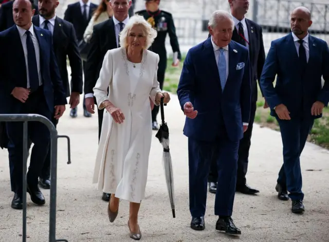 Britain's King Charles and Queen Camilla walk following a service at the Basilica of St Paul's Outside the Walls