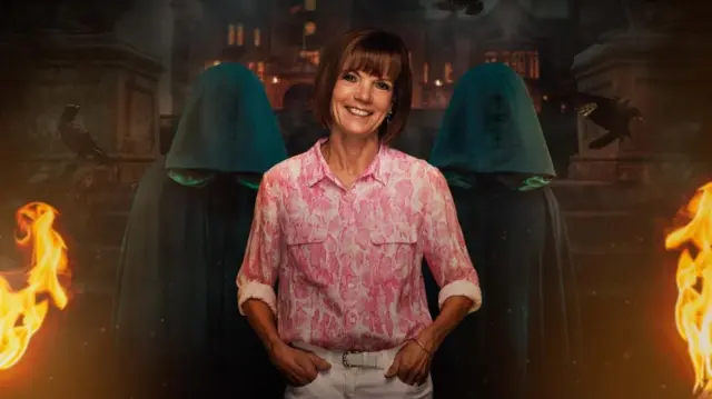 Diane smiles with her hands in her pockets in front of a background displaying two cloaked figures
