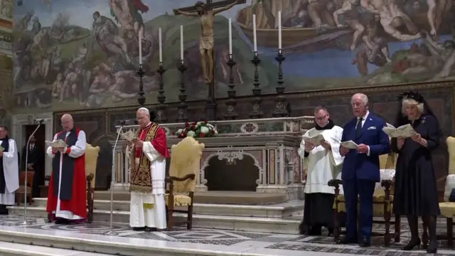 Pope, King and Camilla in the Sistine Chapel - they are standing far apart all reading from a hymn book.