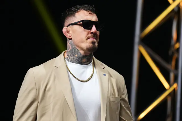 Tom Aspinall in sunglasses and beige suit