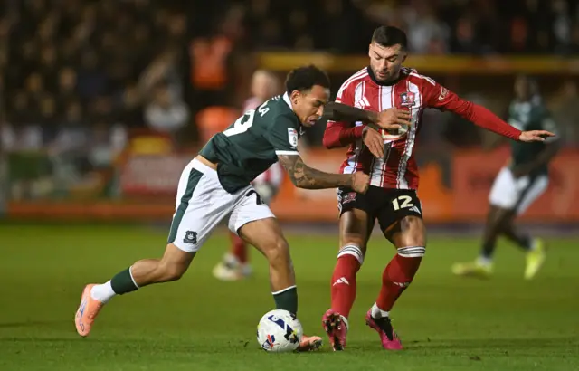 Matthew Sorinola of Plymouth Argyle battles for possession with Reece Cole of Exeter City