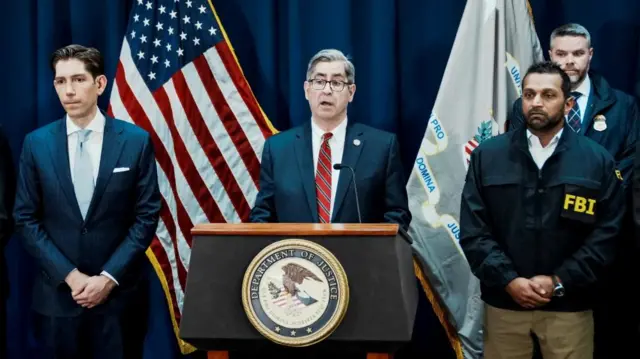 US Attorney for the Eastern District of New York Joseph Nocella, Jr. speaks from behind a lectern bearing the seal of the US Department of Justice, surrounded by other law enforcement officials, including FBI director Kash Patel to the right of the image