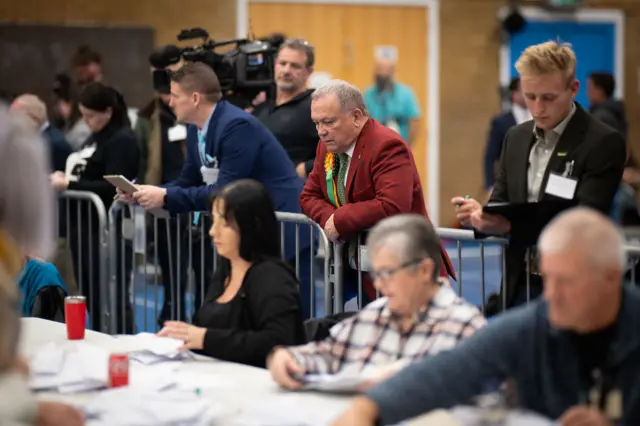 Politicians leaning on a barrier as people count in front of them