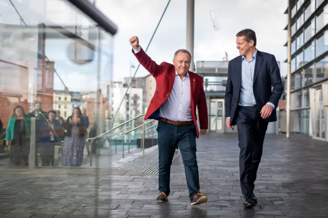 Lindsay Whittle alongside Rhun ap Iorwerth. Whittle has his arm in the arm to celebrate while ap Iorwerth smiles at him.