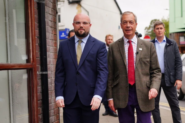 Reform UK leader Nigel Farage (centre) campaigning in Caerphilly, South Wales, with his party's candidate, Llyr Powell