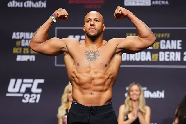 Ciryl Gane holds up his arms as he weighs in for a UFC heavyweight title fight