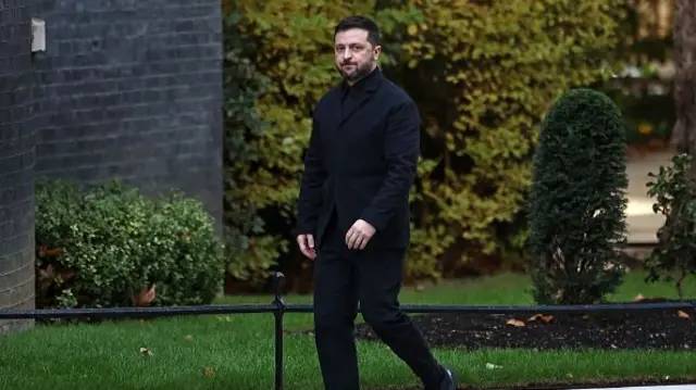 President Zelensky, dressed in all black, walking over to 10 Downing Street