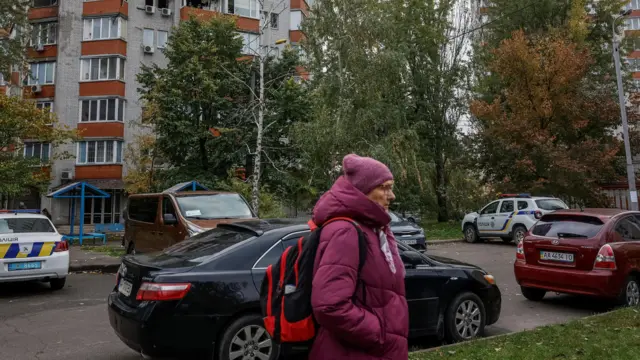 A woman passes by a residential building damaged during a Russian drone and missile strike