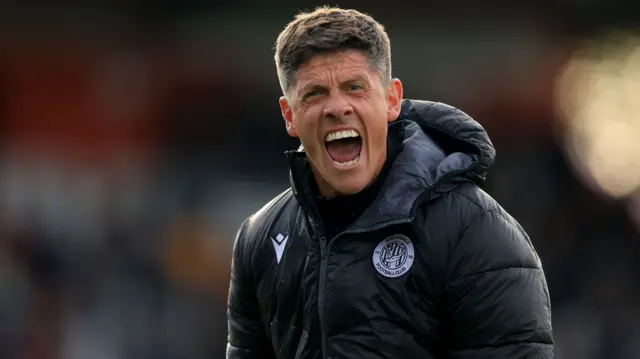 A celebrating Stevenage boss Alex Revell