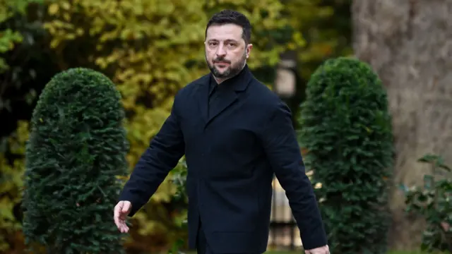 Volodymyr Zelensky in black blazer and shirt as he walks along the pavement outside Number 10