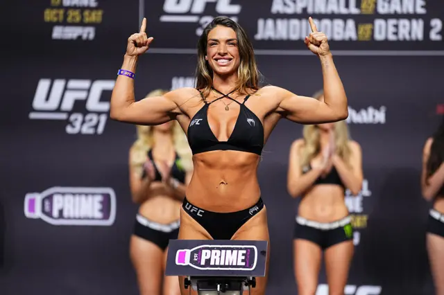 Mackenzie Dern holds up a finger as she weighs in for a UFC strawweight title fight