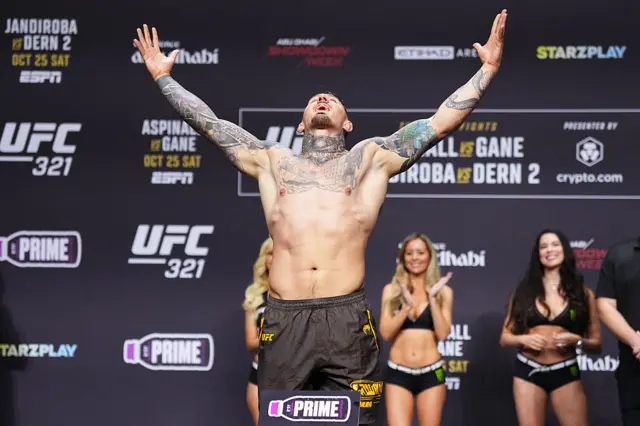 Tom Aspinall holds up his arms as he weighs in for a UFC heavyweight title fight