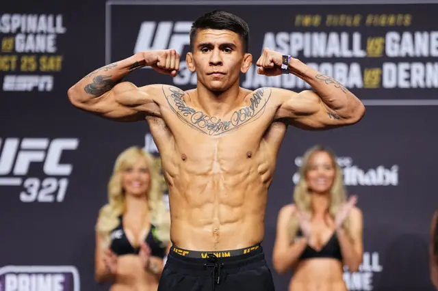 Mario Bautista holds up his arms as he weighs in for a UFC fight