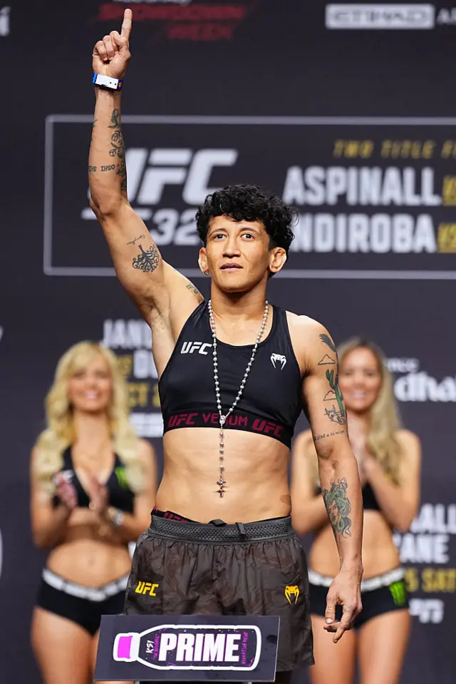 Virna Jandiroba holds up her arms as she weighs in for a UFC strawweight title fight