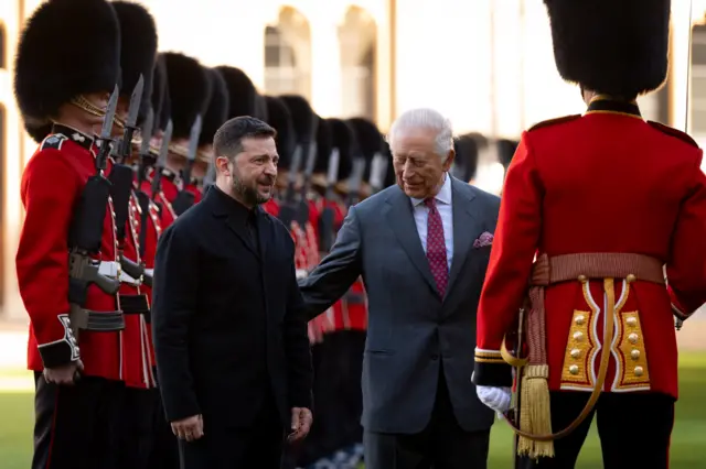 The King pats Zelensky on the back as they inspect a guard of honour