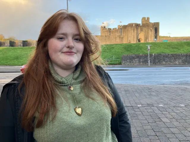 Freya Jenkins wearing a green jumper, dark jacket and a gold necklance