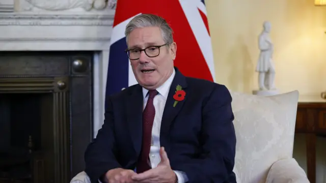 Keir Starmer in a cream chair in front of a fireplace