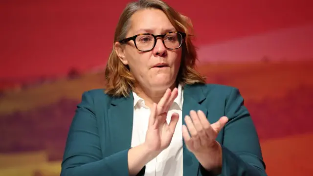 Anna Turley claps in front of a red background