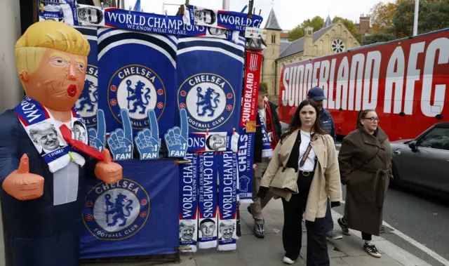A Chelsea merch stall with a blow up Donald Trump doll