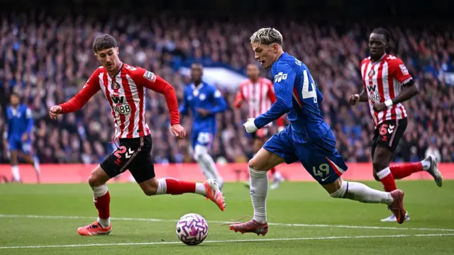 Alejandro Garnacho crosses the ball whilst under pressure from Trai Hume
