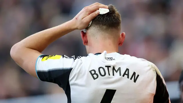 Sven Botman of Newcastle United leaves the pitch holding a bandage on his head