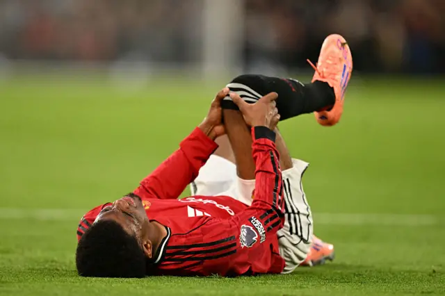 Amad Diallo holds his leg after a challenge