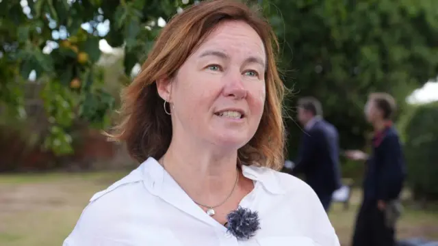 Woman i white shirt and label mic speaking